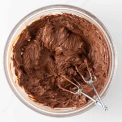 Mixing chocolate frosting in a glass bowl.