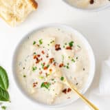 Clam chowder in a white bow with gold spoon.