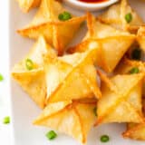 Crab rangoon on a plate with sweet and sour sauce.