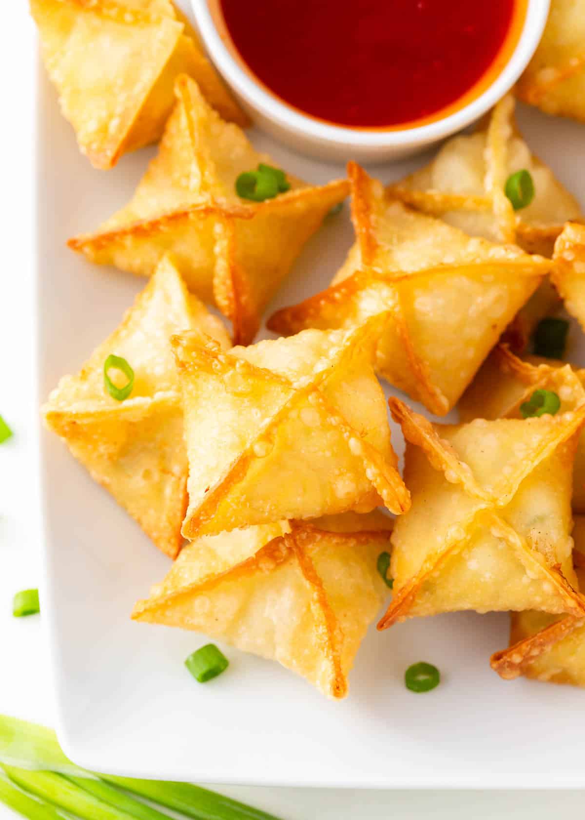 Crab rangoon on a plate with sweet and sour sauce.