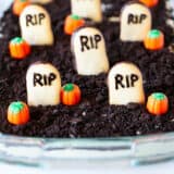 Halloween dirt cake in a glass dish with pumpkins on top.