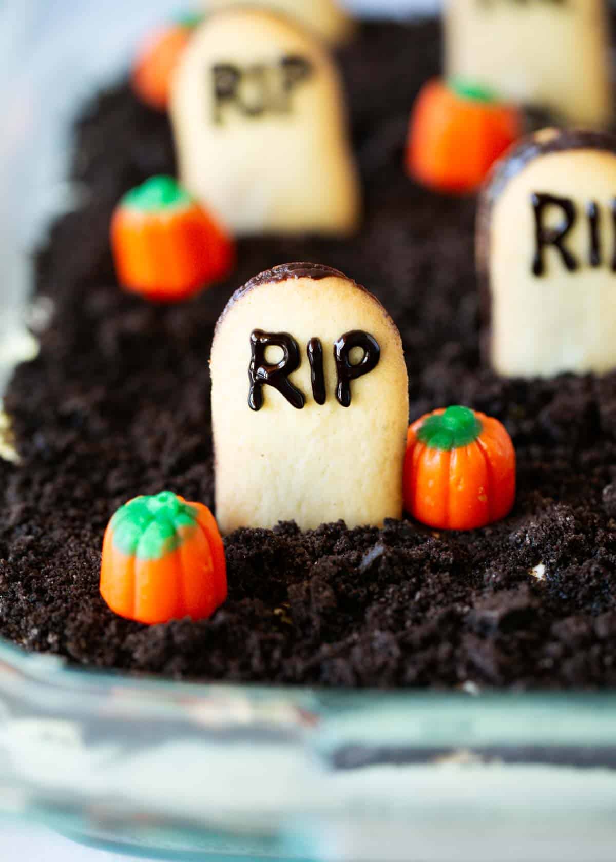 Oreo dirt cake in a glass dish with pumpkins on top.