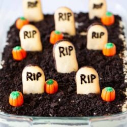 Oreo dirt cake in a glass dish with cookies and pumpkins on top.
