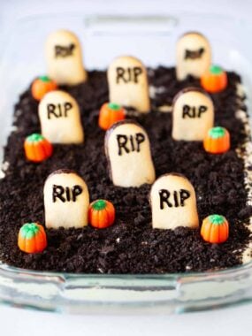 Oreo dirt cake in a glass dish with cookies and pumpkins on top.