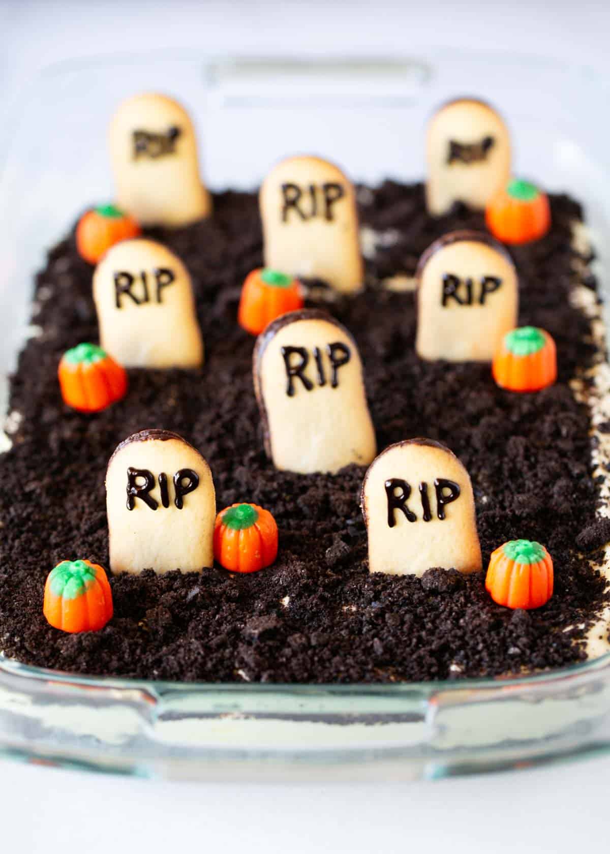 Oreo dirt cake in a glass dish with cookies and pumpkins on top.