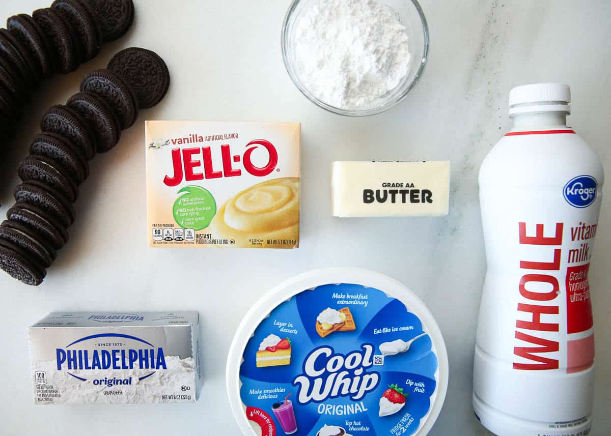 Alt text: Halloween dirt cake ingredients including Oreos, vanilla instant pudding mix, butter, powdered sugar, cream cheese, Cool Whip and whole milk.