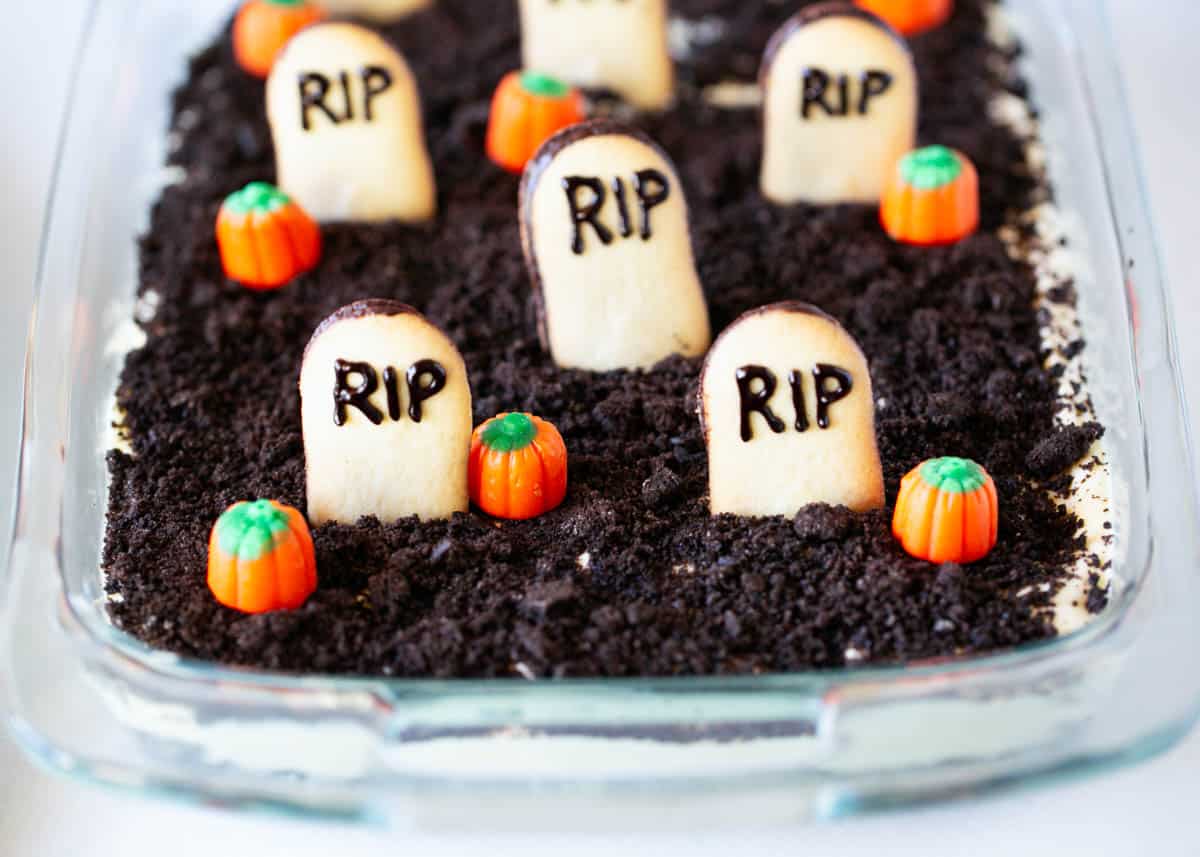 Halloween dirt cake in a glass dish with pumpkins on top.