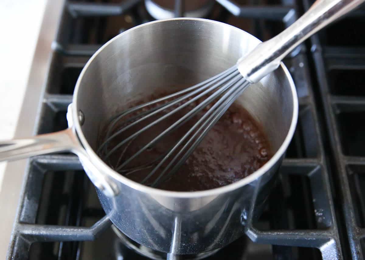 Whisking chocolate icing in a pot.