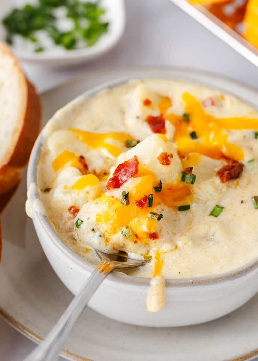 This loaded baked potato soup is the best comfort food! Made with tender potatoes, cheese, bacon and sour cream, it is a creamy and cozy soup recipe to enjoy all fall! Loaded baked potato soup in a bowl topped with cheese and bacon.