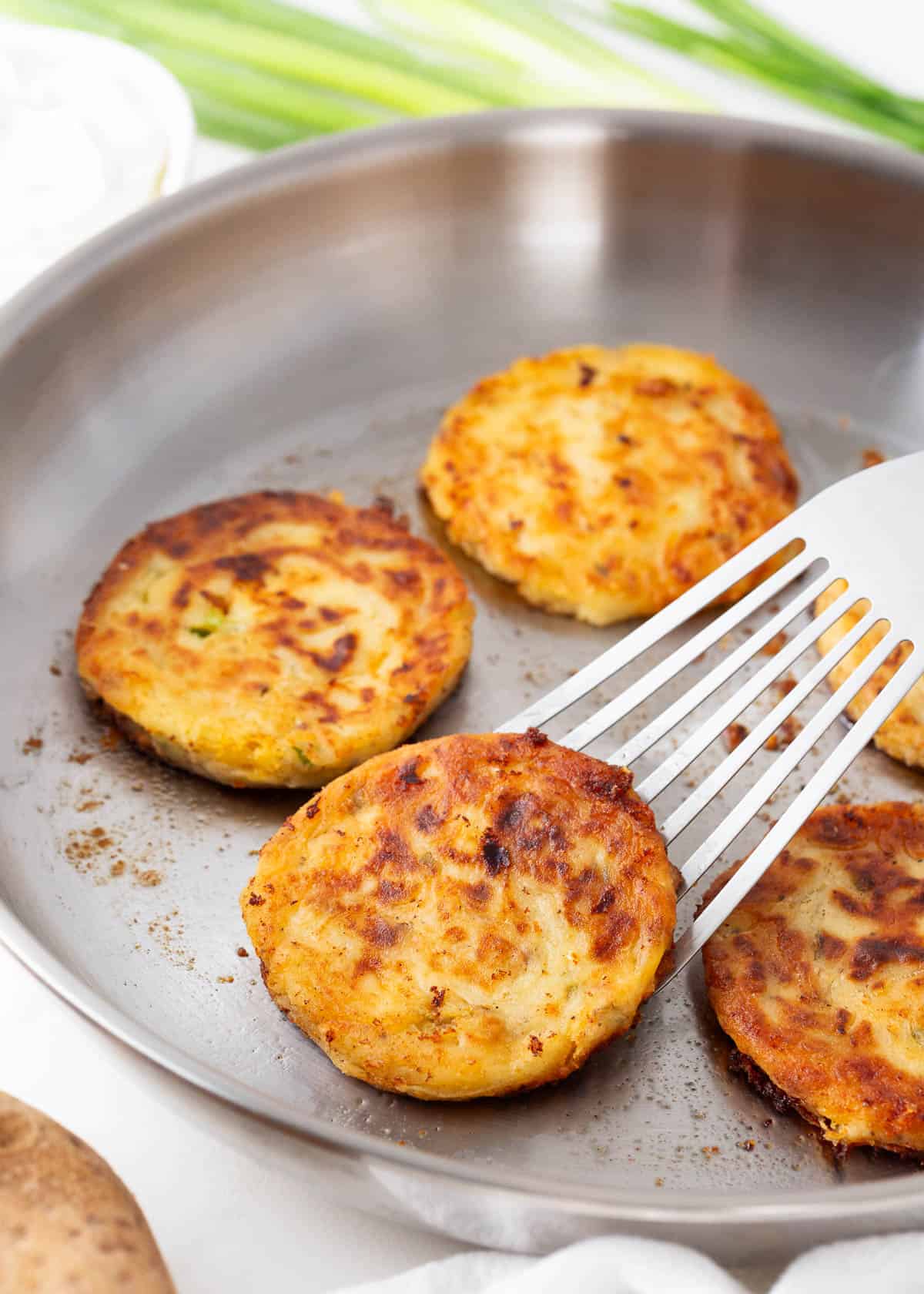 Cooking mashed potato pancakes in a skillet.