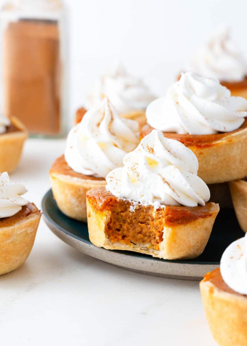 Mini pumpkin pies with whipped cream on a plate.