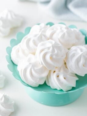 Meringue cookies in a colored bowl on the counter.