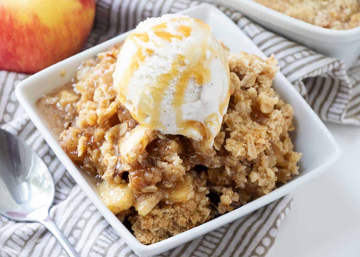 This easy apple crisp has a sweet apple base and is topped with a buttery oatmeal streusel topping that's baked to perfection. So comforting and delicious! Apple crisp and ice cream in a bowl.