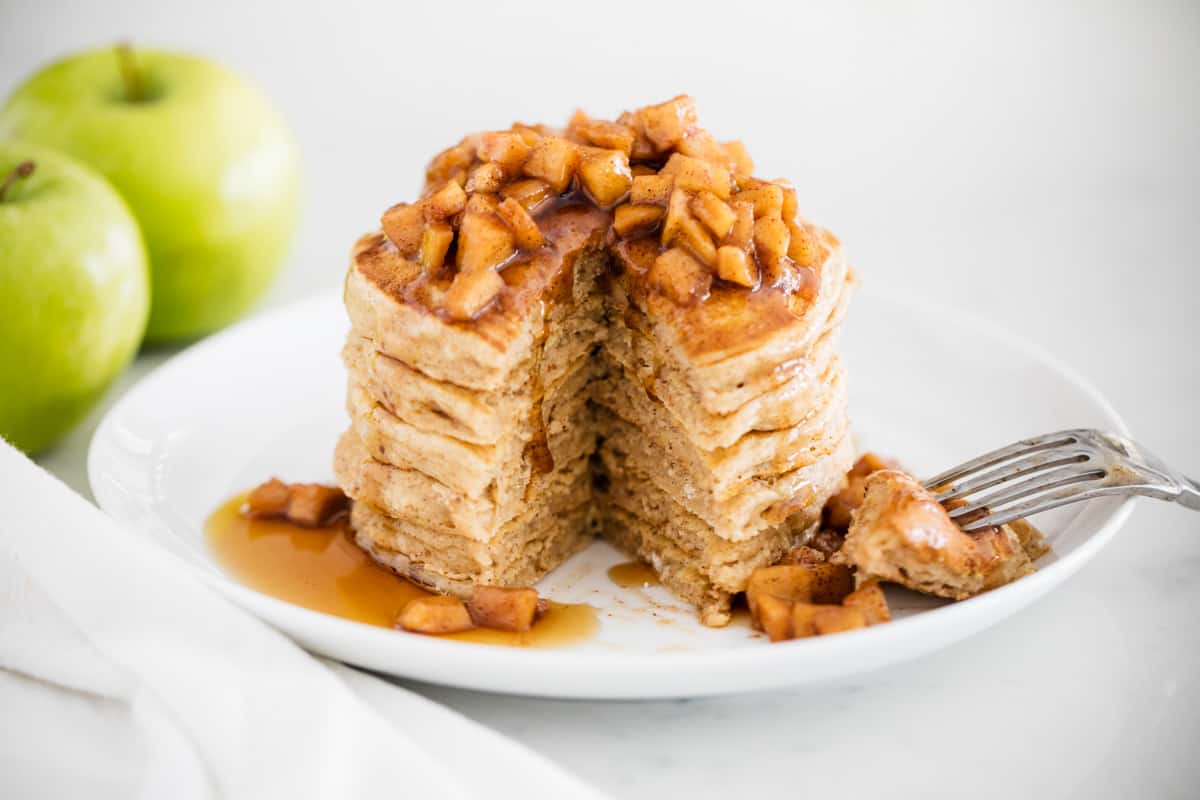 Fluffy apple pancakes with a hint of cinnamon and grated apples baked right into the center. These are the perfect fall breakfast! Apple pancakes stacked on top of each other.