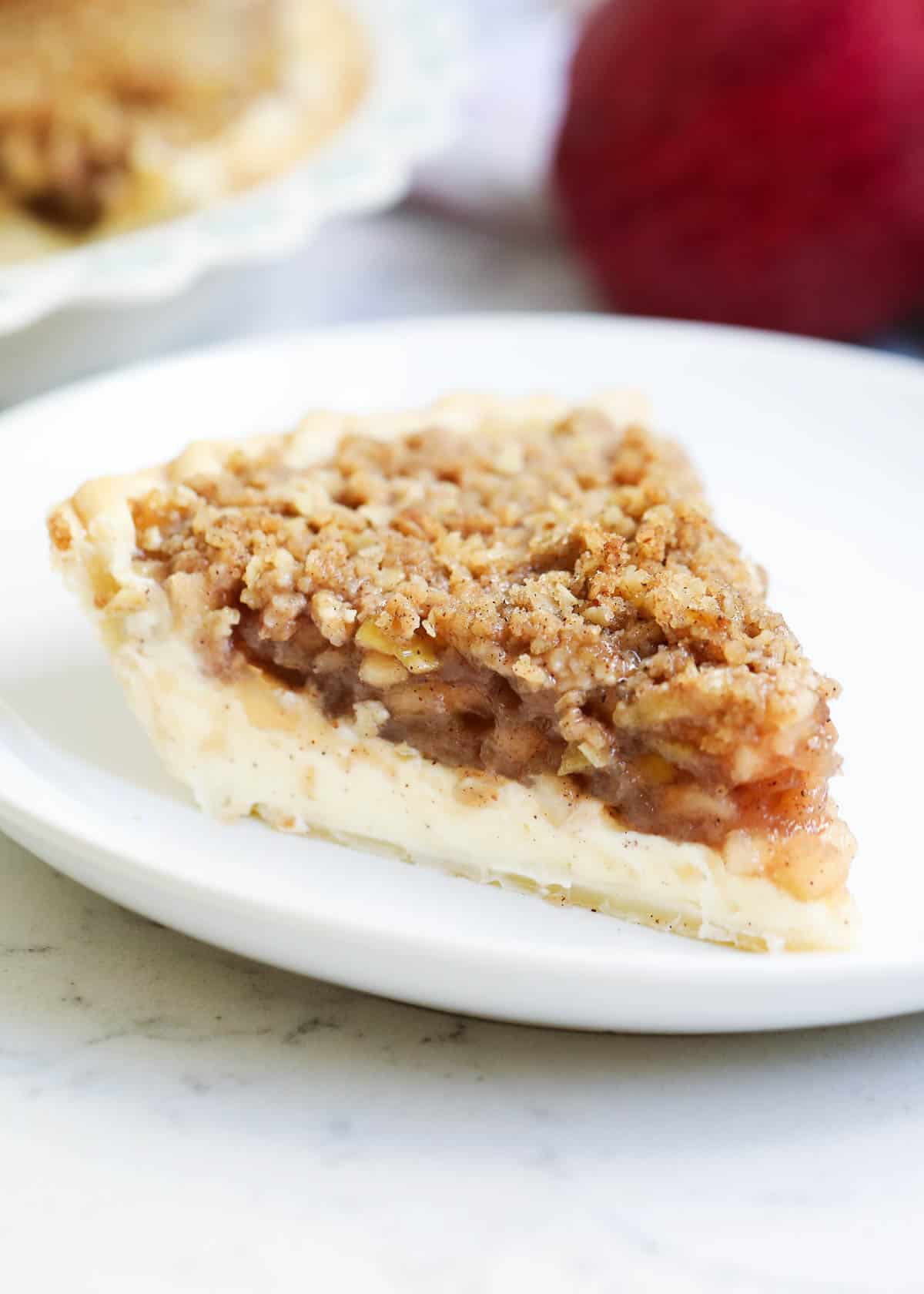 A slice of apple pie cheesecake on a plate. 