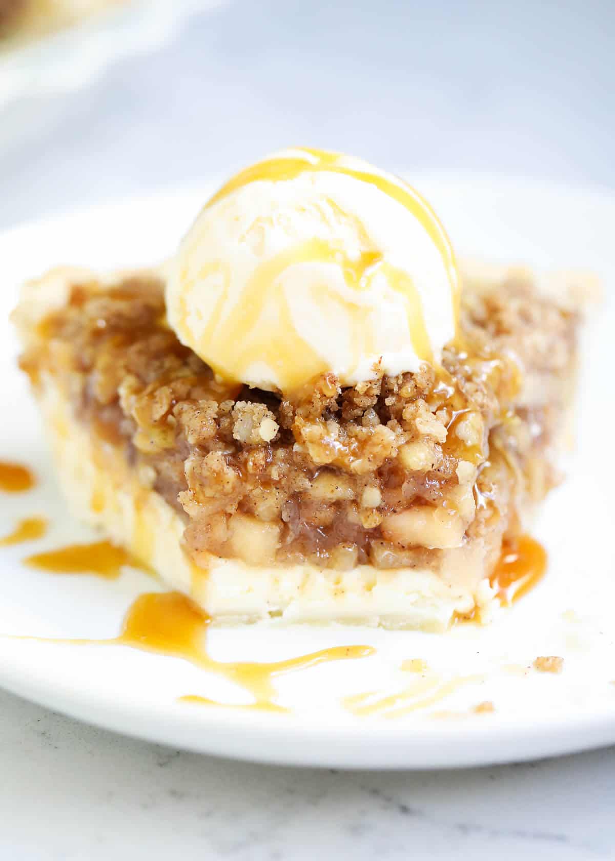 A slice of apple pie cheesecake with a scoop of ice cream on top. 