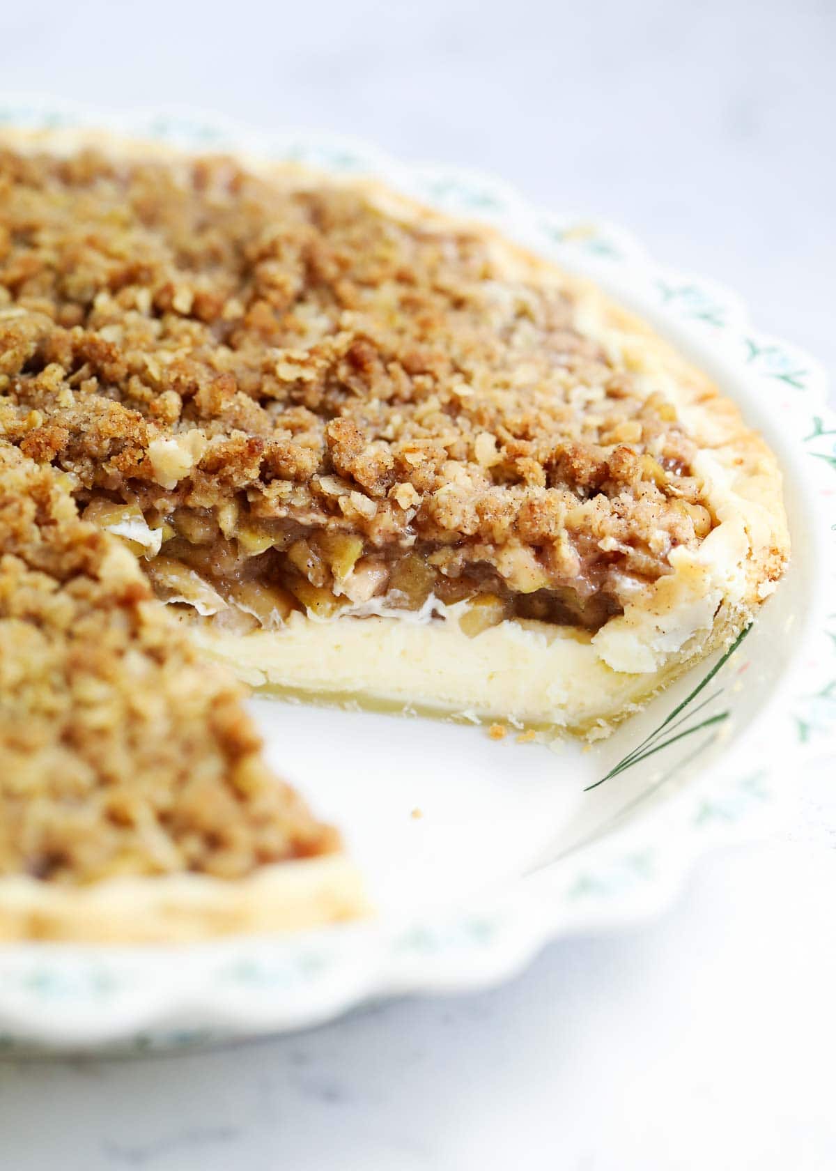 Apple pie cheesecake with a slice taken out of it. 