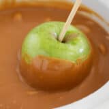 Dipping apple into caramel.