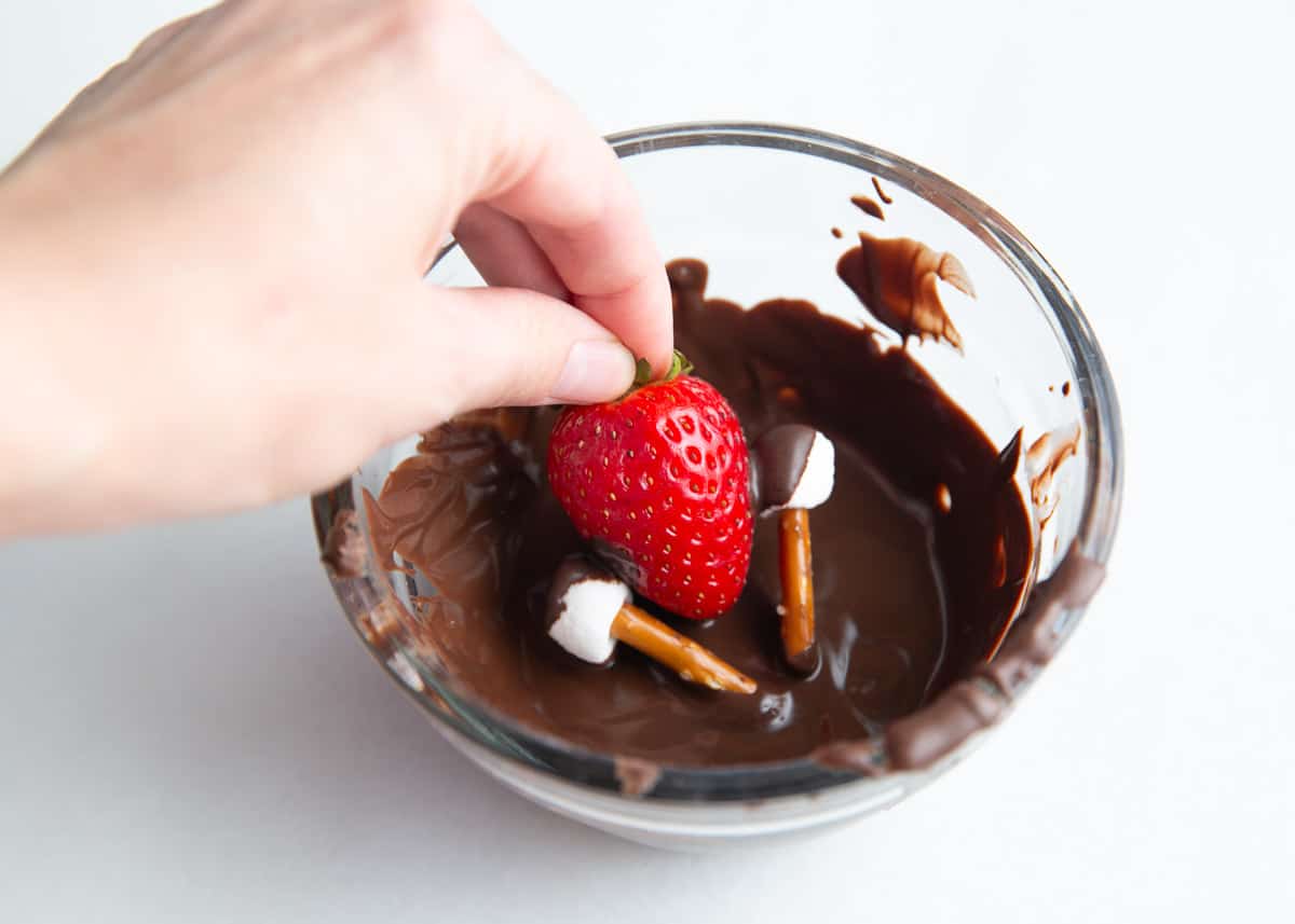 Dipping strawberry in chocolate.