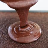 Pouring chocolate icing over cake.