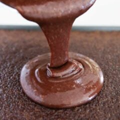Pouring chocolate icing over cake.