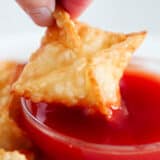 Dipping cream cheese wontons in sweet and sour sauce.