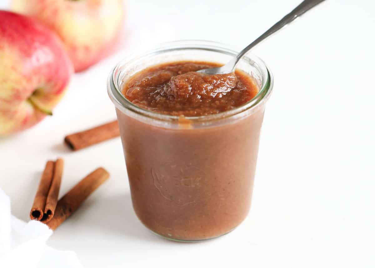 Apple butter in a glass jar with spoon.