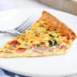 Slice of quiche on white plate.