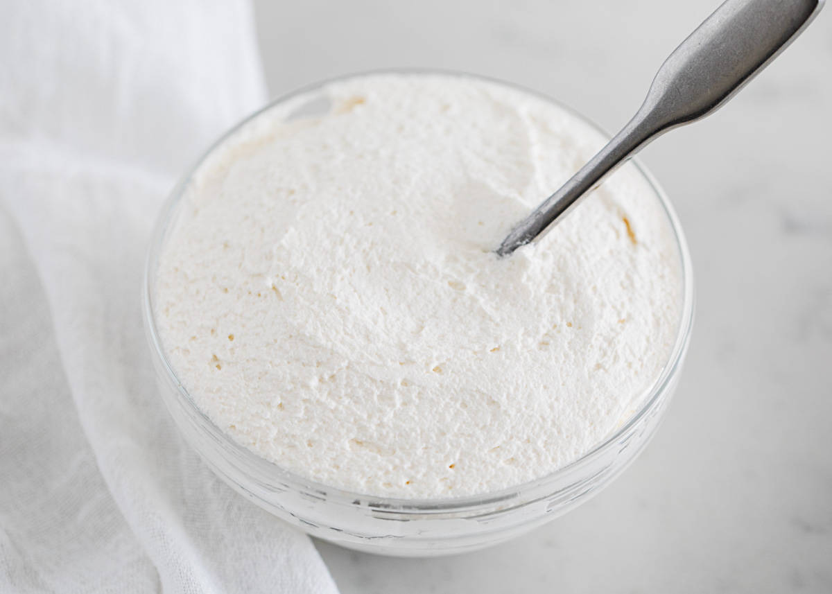 Learn how to make cool whip with just 4 simple ingredients! It's perfectly light and fluffy with amazing flavor. Makes a great topping for so many of your favorite desserts! Homemade cool whip in a bowl.