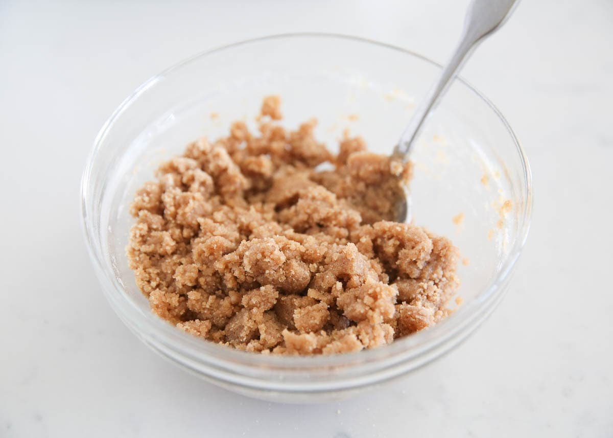 Bowl of homemade brown sugar crumble topping with a spoon, showing a coarse, sandy texture.
