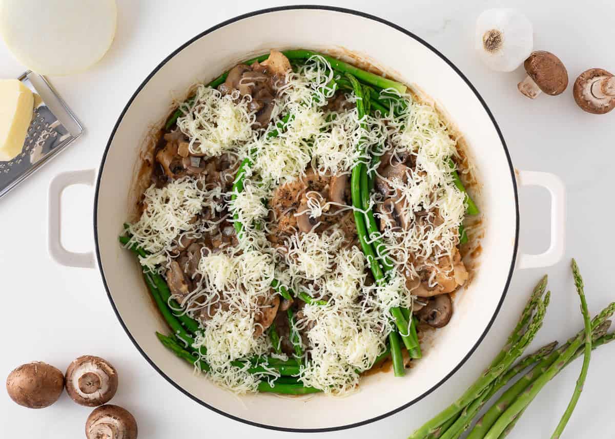Chicken Madeira topped with mushrooms, asparagus, and shredded cheese before melting.