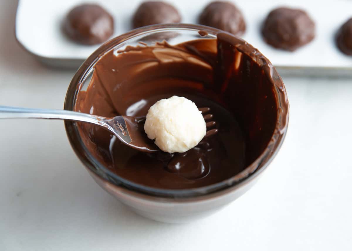 Dipping a coconut ball into chocolate. 