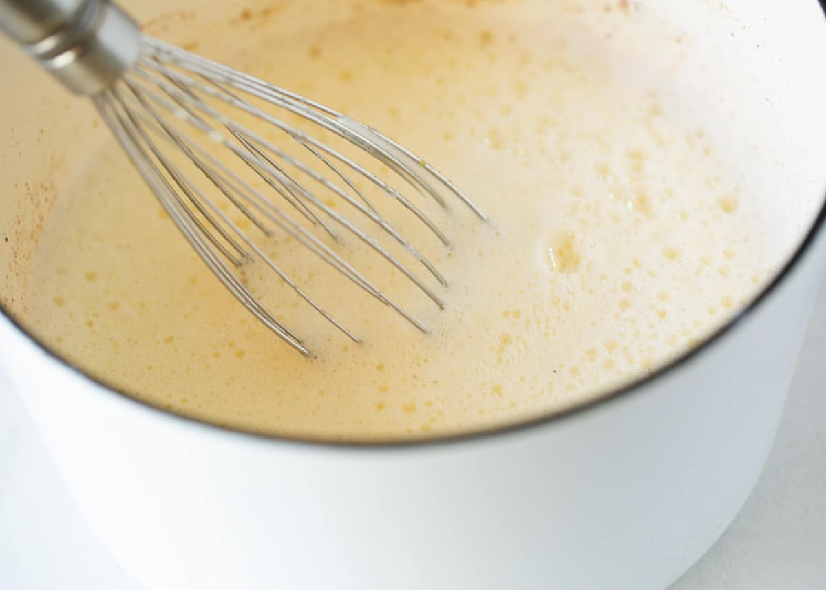 Whisking eggnog in a pot.