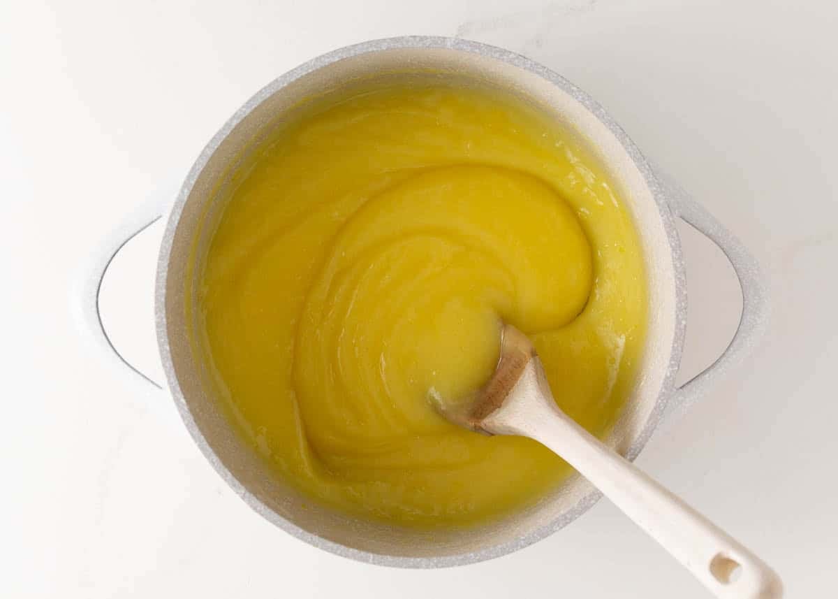Thick lemon pie filling stirred in a saucepan for homemade lemon meringue pie.
