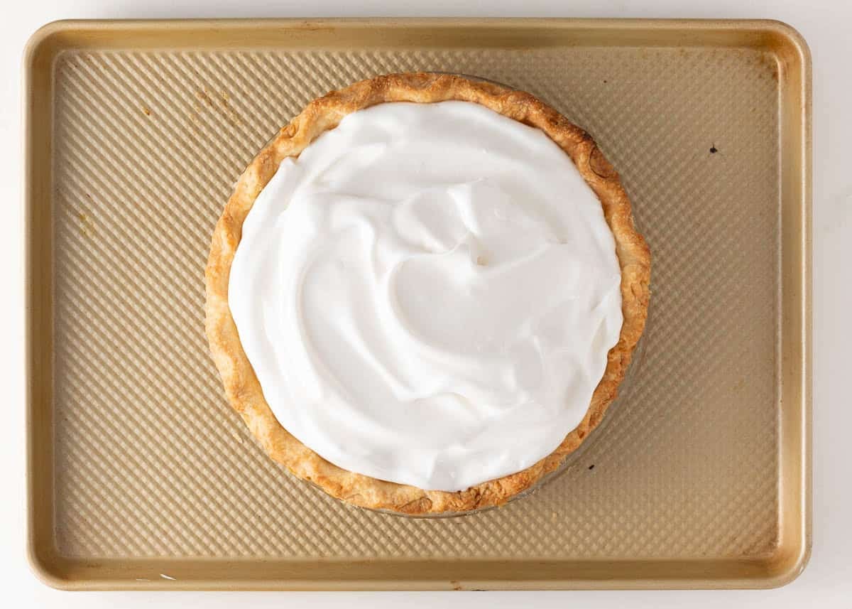 Lemon meringue pie topped with unbaked meringue spread to the edges of the crust before baking.