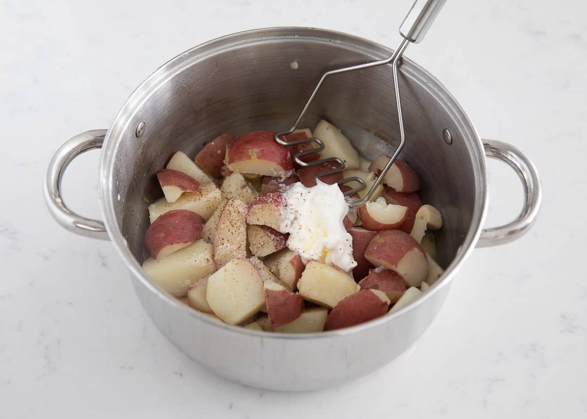 Mashing red potatoes in a pot.