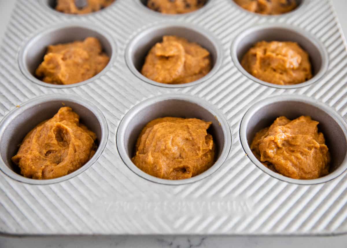 Pumpkin muffin batter in a muffin tin.