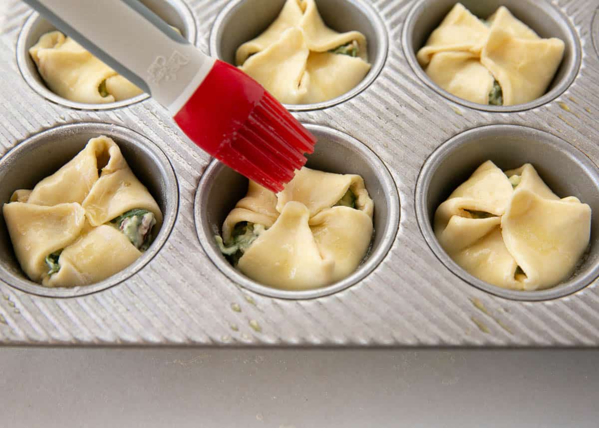 Brushing the butter onto the spinach puffs.