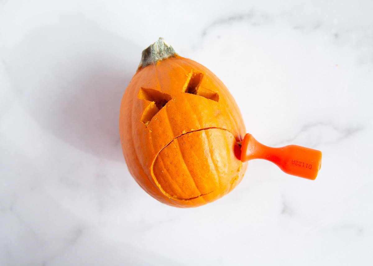 Carving a mini pumpkin.