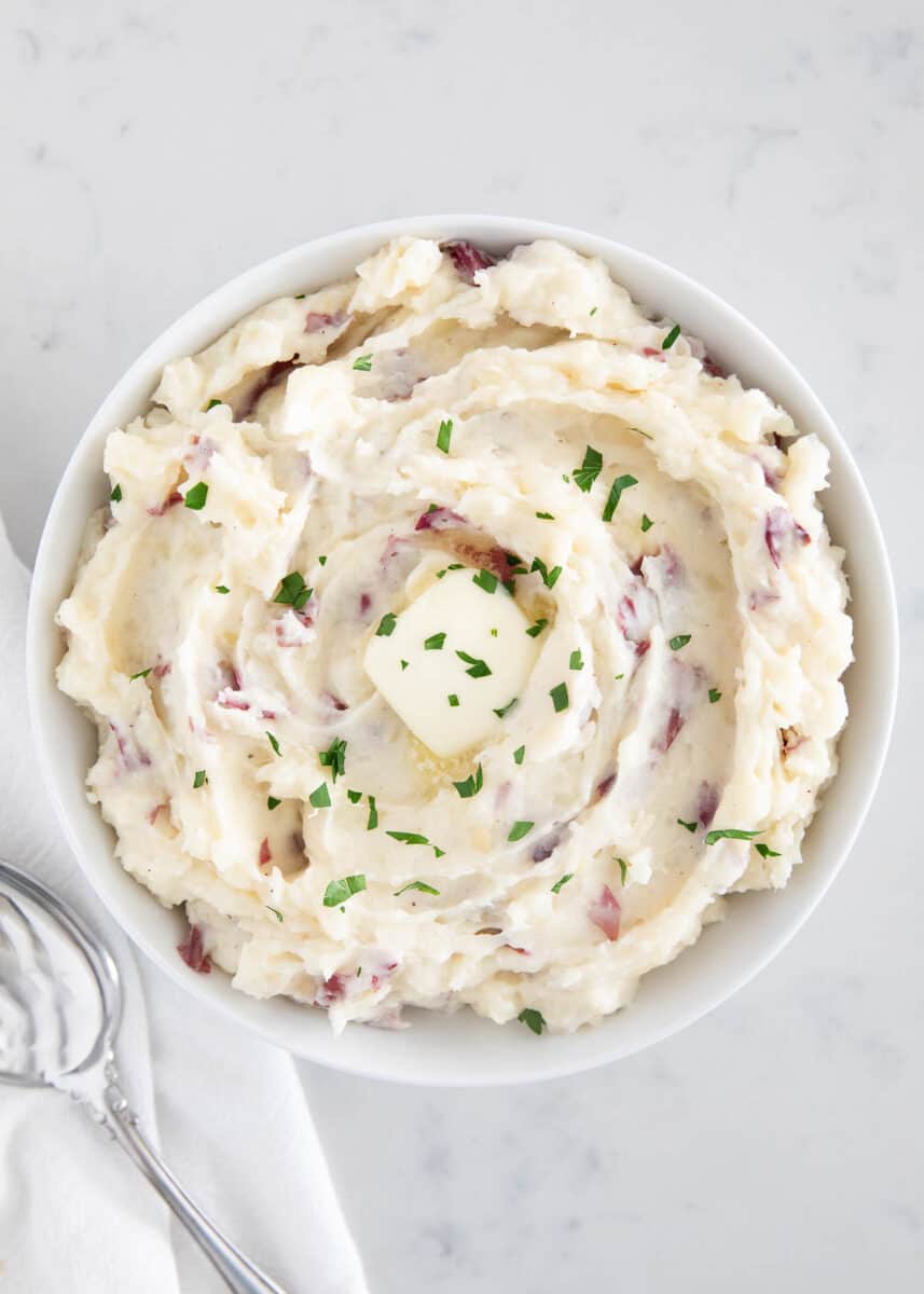 Mashed red potatoes in a white bowl.