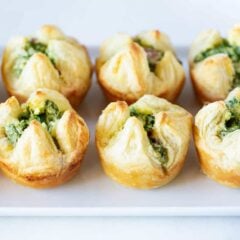 Two rows of spinach puffs on a white serving plate.
