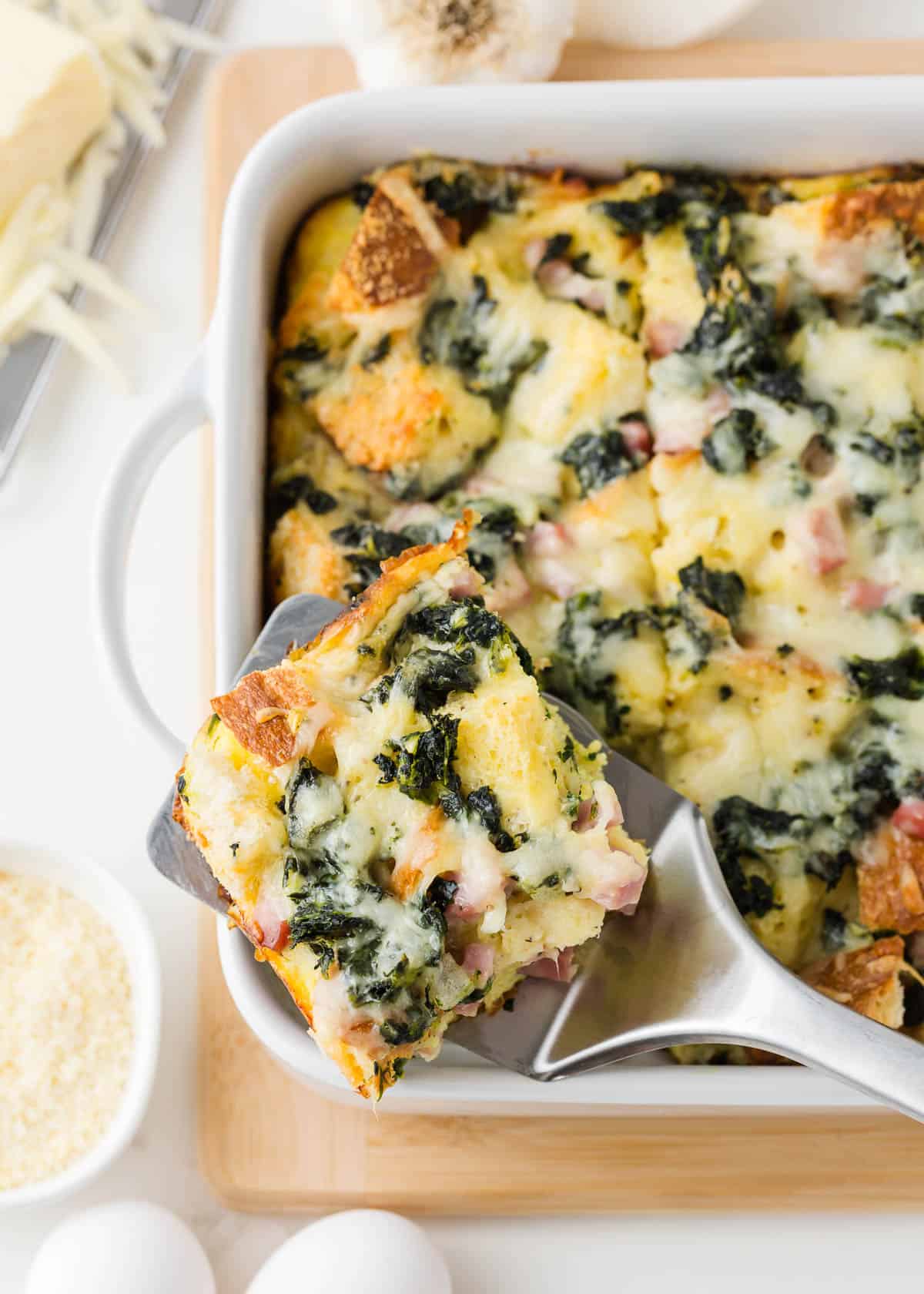 Slice of breakfast strata in a white baking dish.