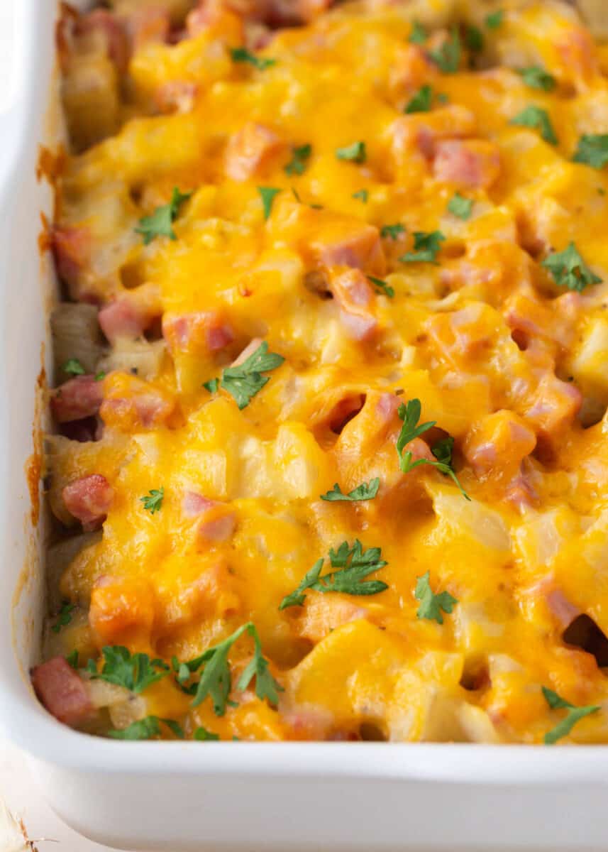 Cheesy ham and potato casserole in a white baking dish.