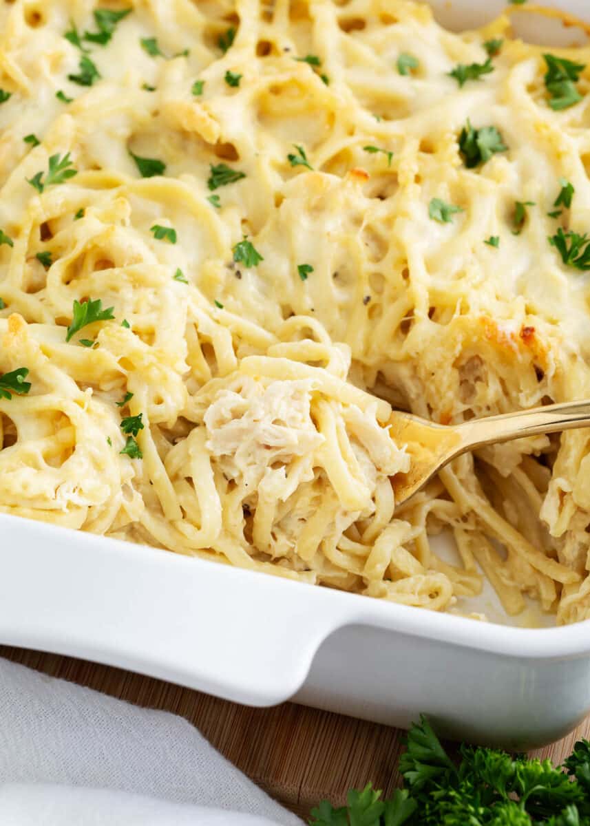 Spoonful turkey tetrazzini in a white baking dish.