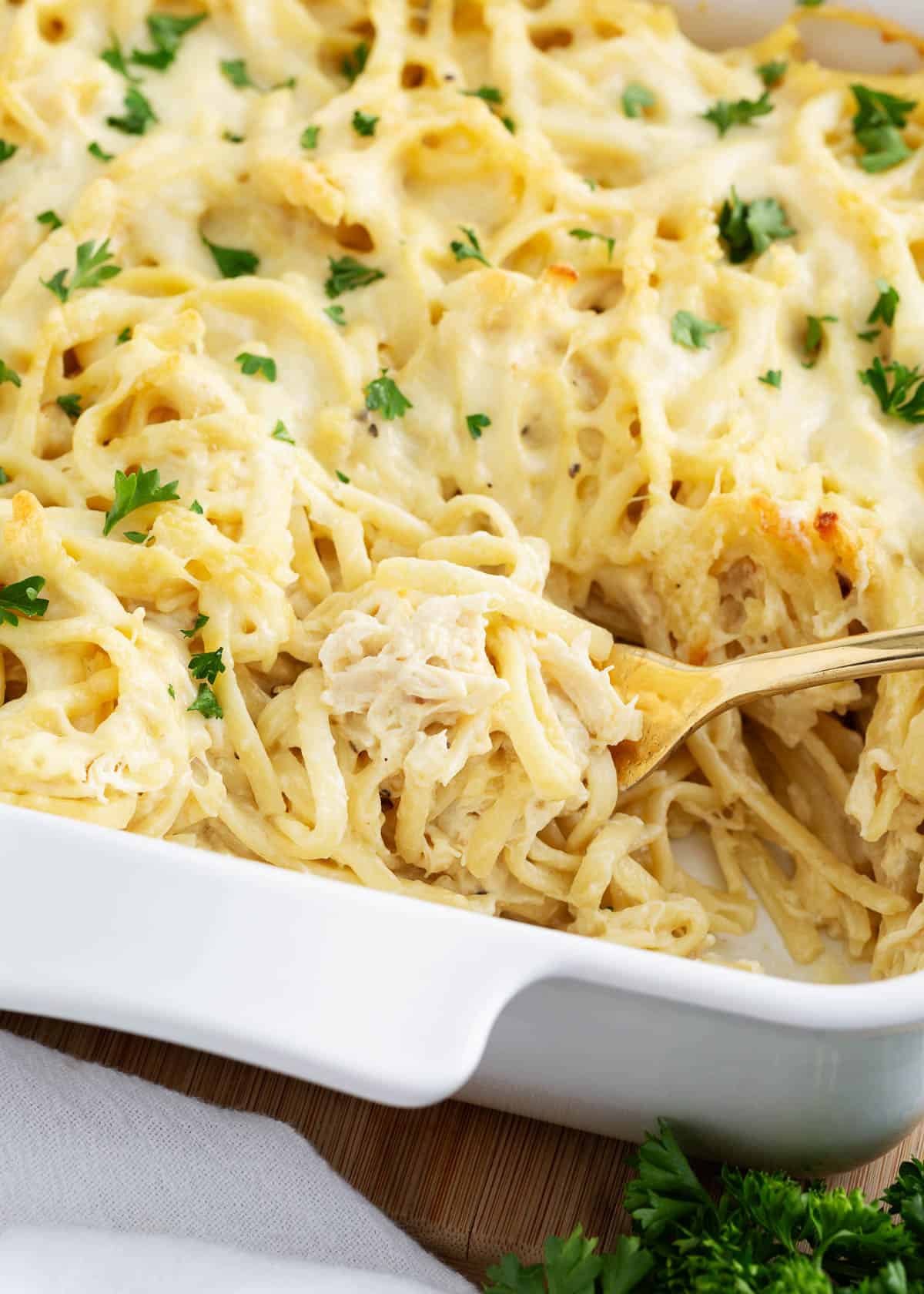 Spoonful of turkey tetrazzini being served from a white baking dish.