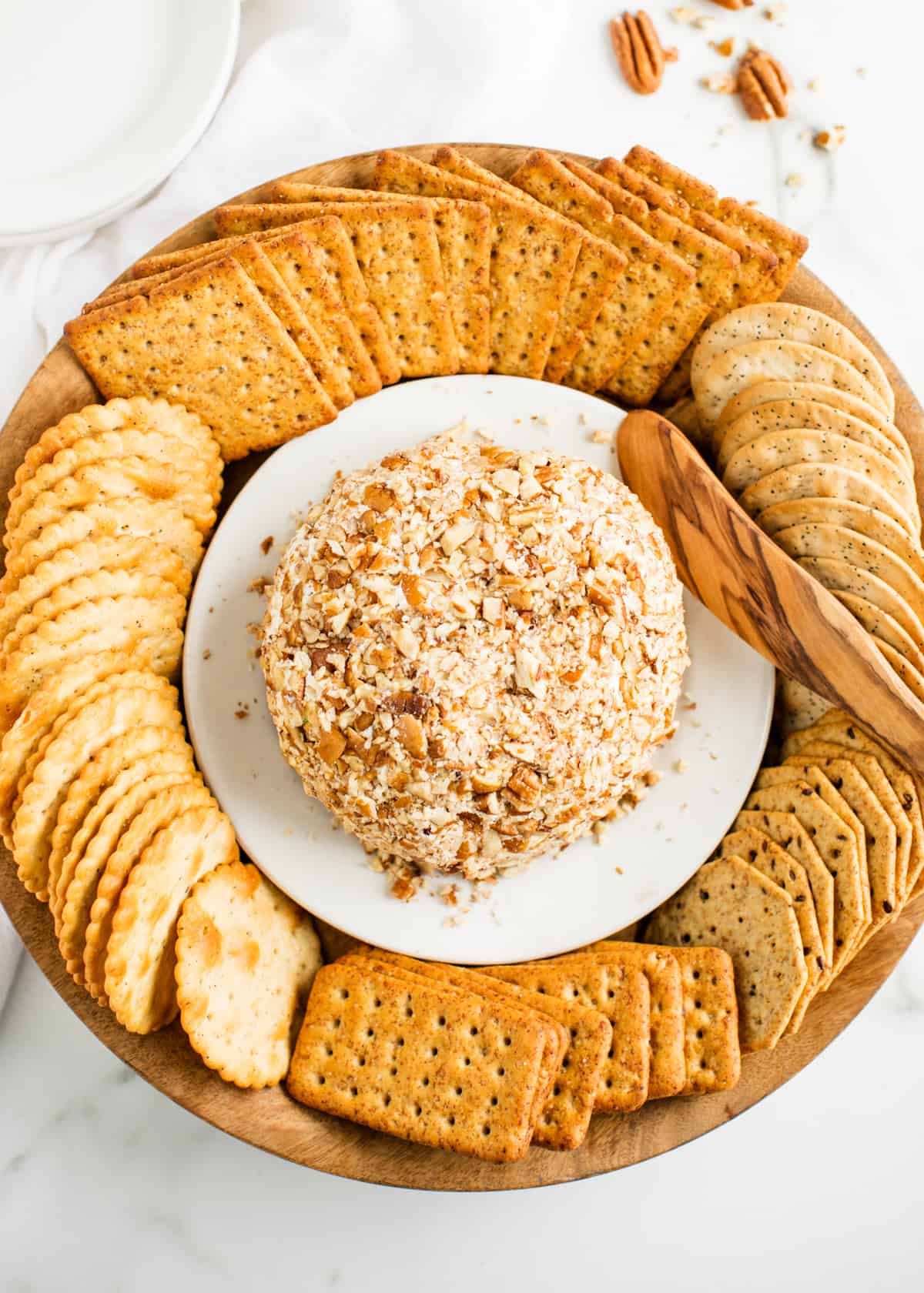 Cheese ball with crackers on a white plate.