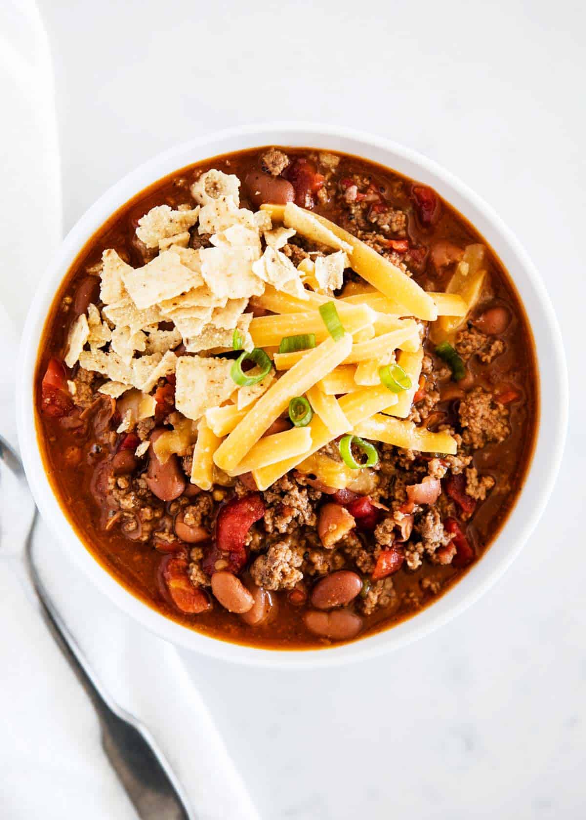 Bowl of easy chili with ground beef, beans and rotel with cheese on top.