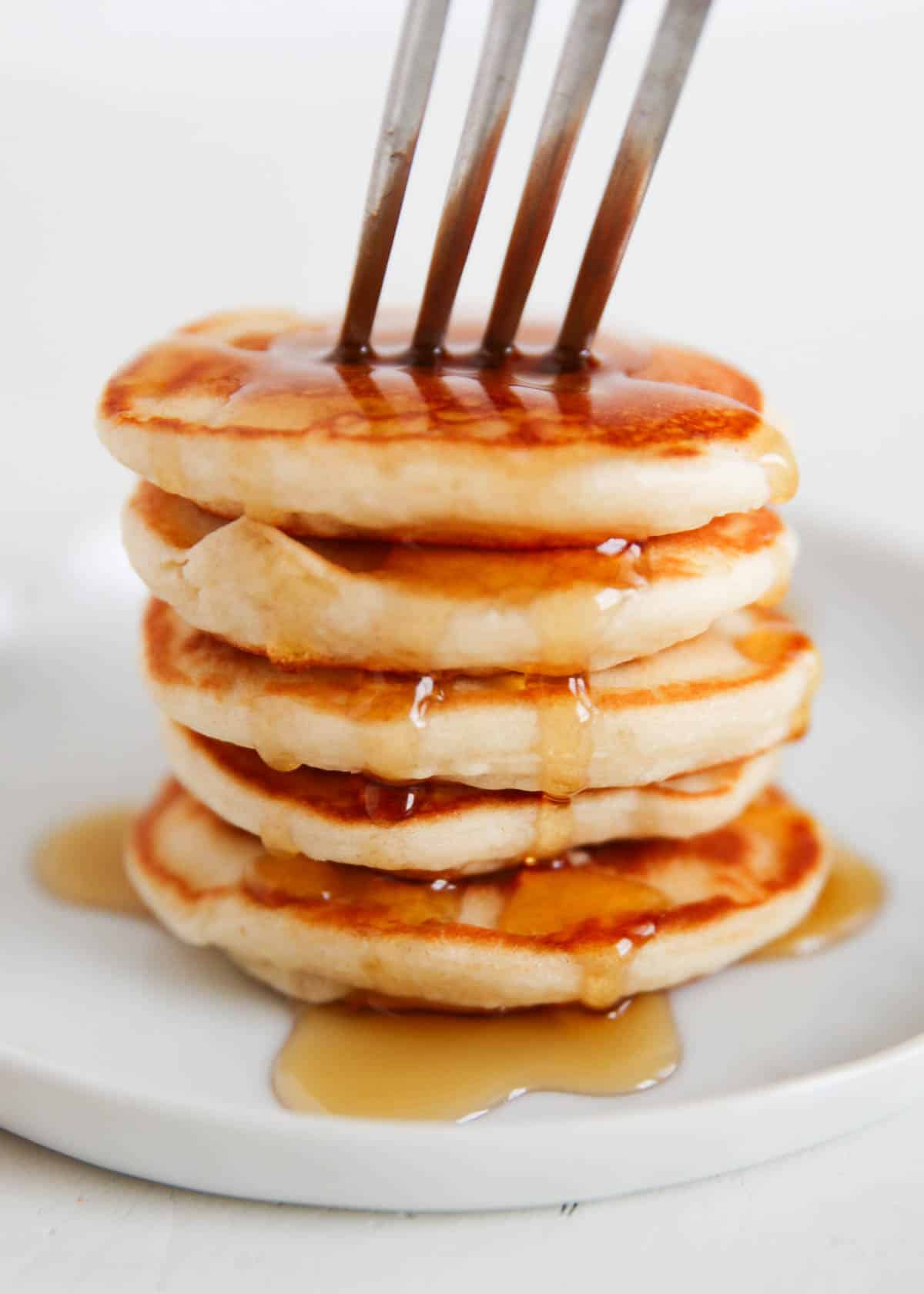Stack of mini silver dollar pancakes with maple syrup.