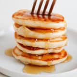 Stack of mini silver dollar pancakes with syrup.