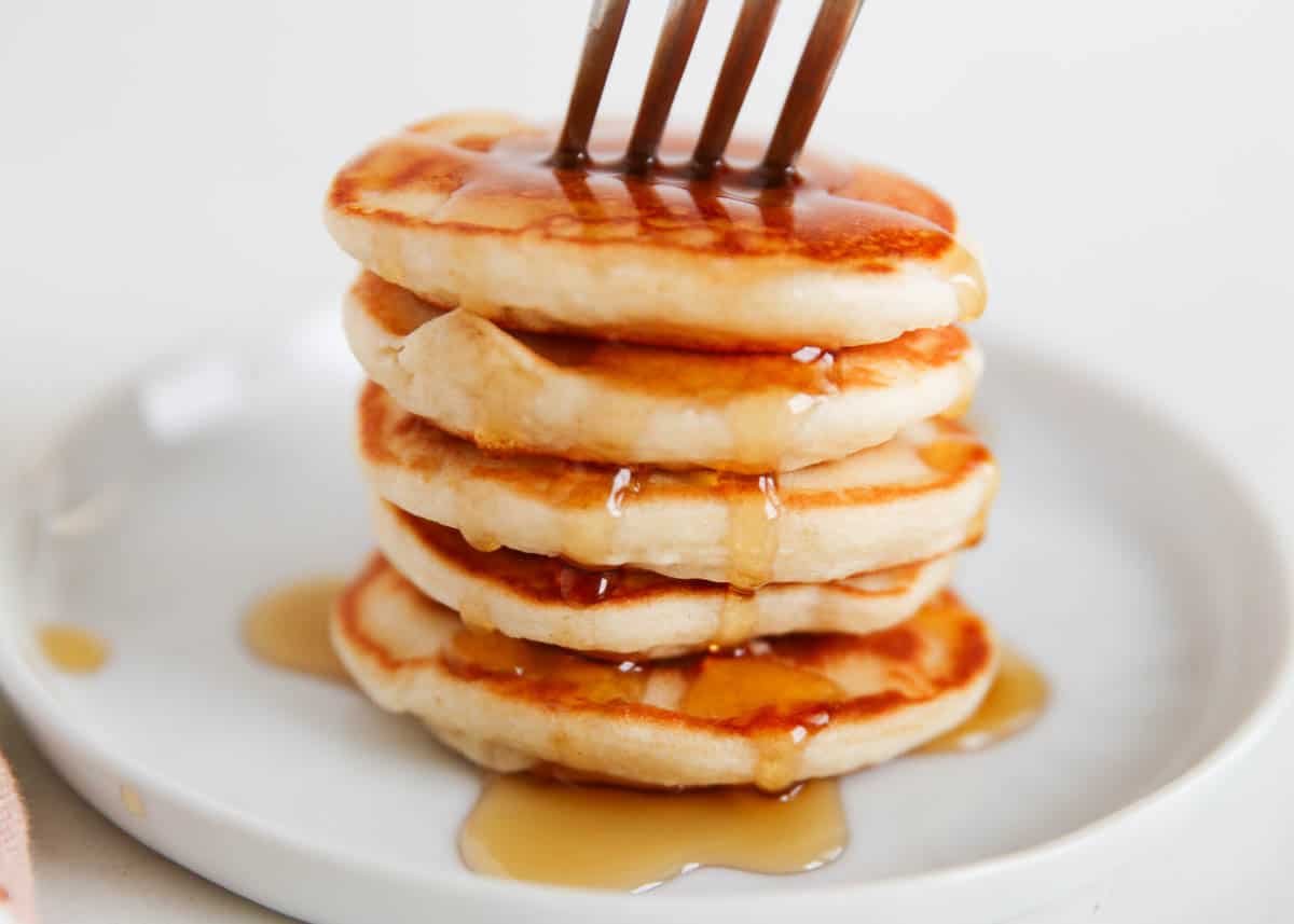 Stack of mini silver dollar pancakes with syrup.
